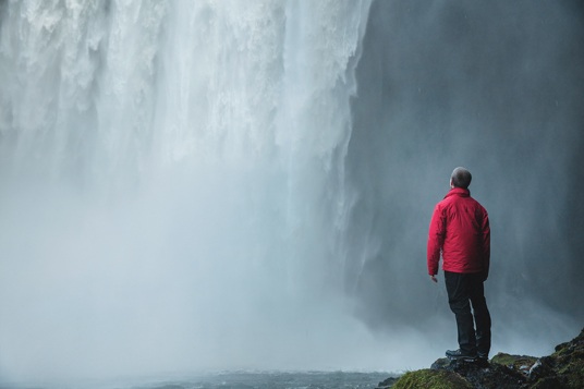 Man in Rainydays jacket enjoying the view of a waterfall